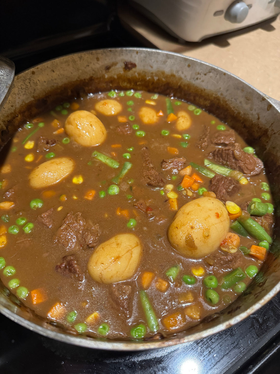 A bowl of dark Cajun beef stew with potatoes and vegetables served over rice