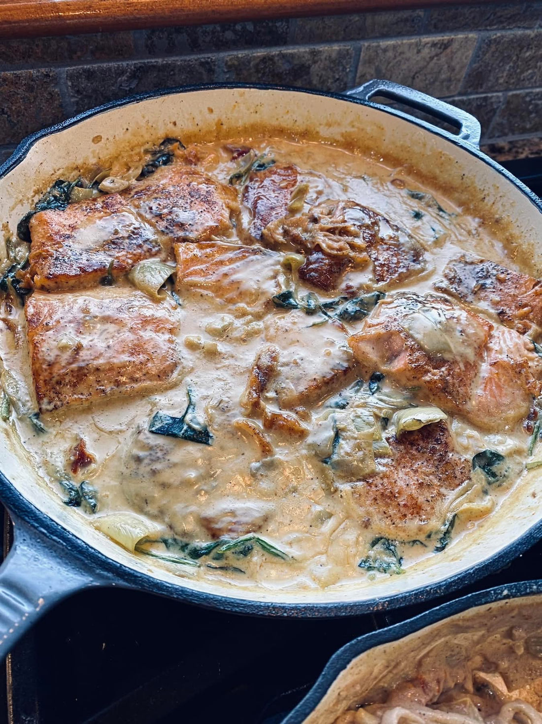 Creamy Tuscan salmon in a skillet with sun-dried tomatoes, artichokes and spinach