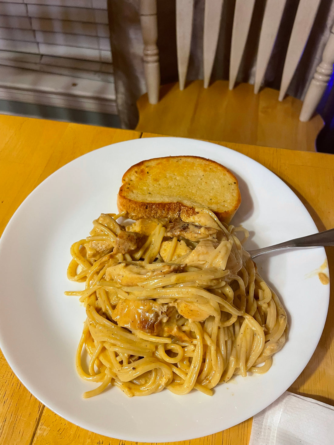 A plate of cheesy chicken spaghetti with grilled chicken and Texas toast