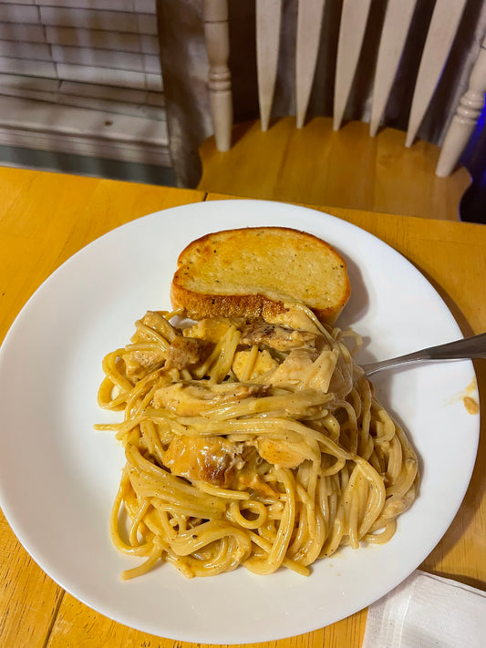 A plate of cheesy chicken spaghetti with grilled chicken and Texas toast
