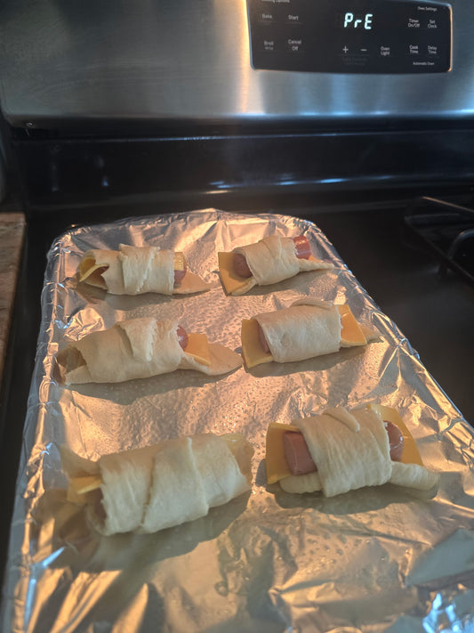 Pigs in a blanket made with crescent rolls and cheddar on a baking sheet
