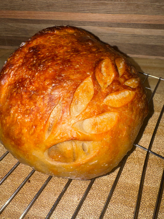 A scored round sourdough loaf baked in a Dutch oven