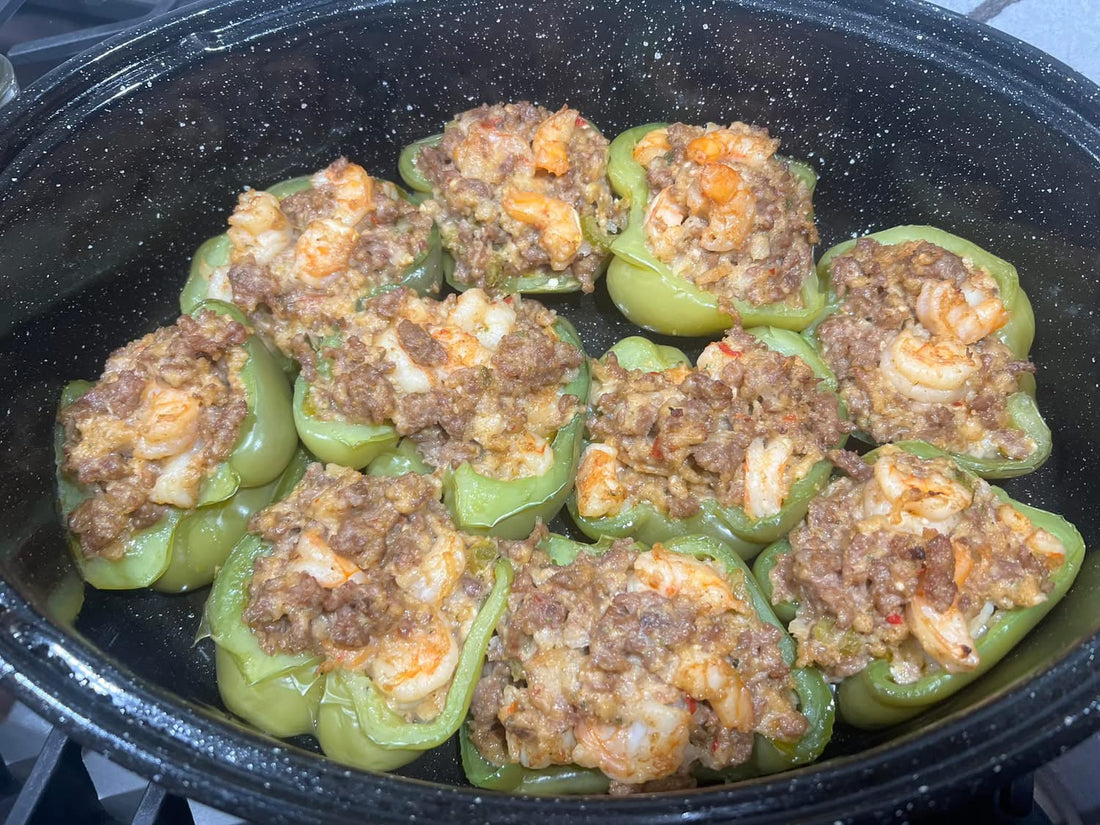 Shrimp and sausage stuffed bell pepper halves in a roasting pan topped with green onions