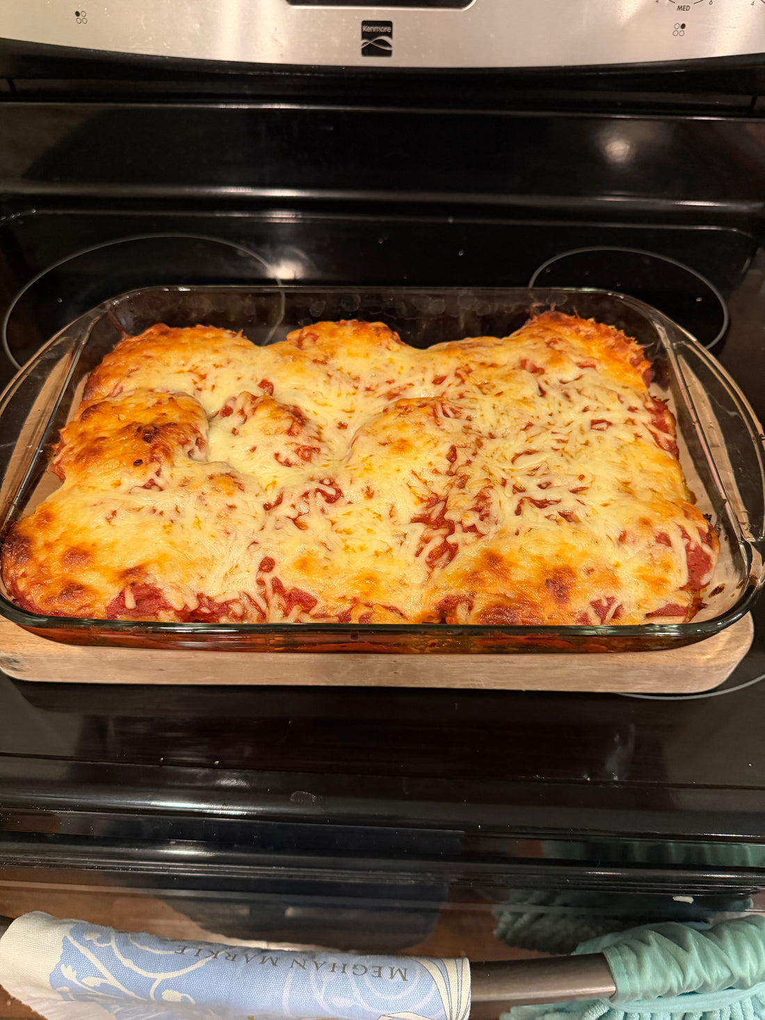 Baked eggplant parmigiana in a casserole dish with melted mozzarella and fresh basil