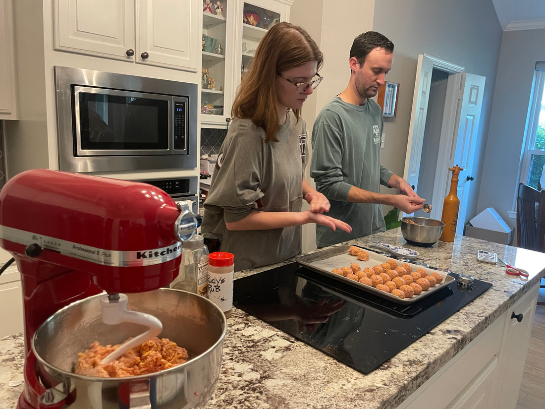 Sausage cheese balls being rolled and placed on a lined baking sheet