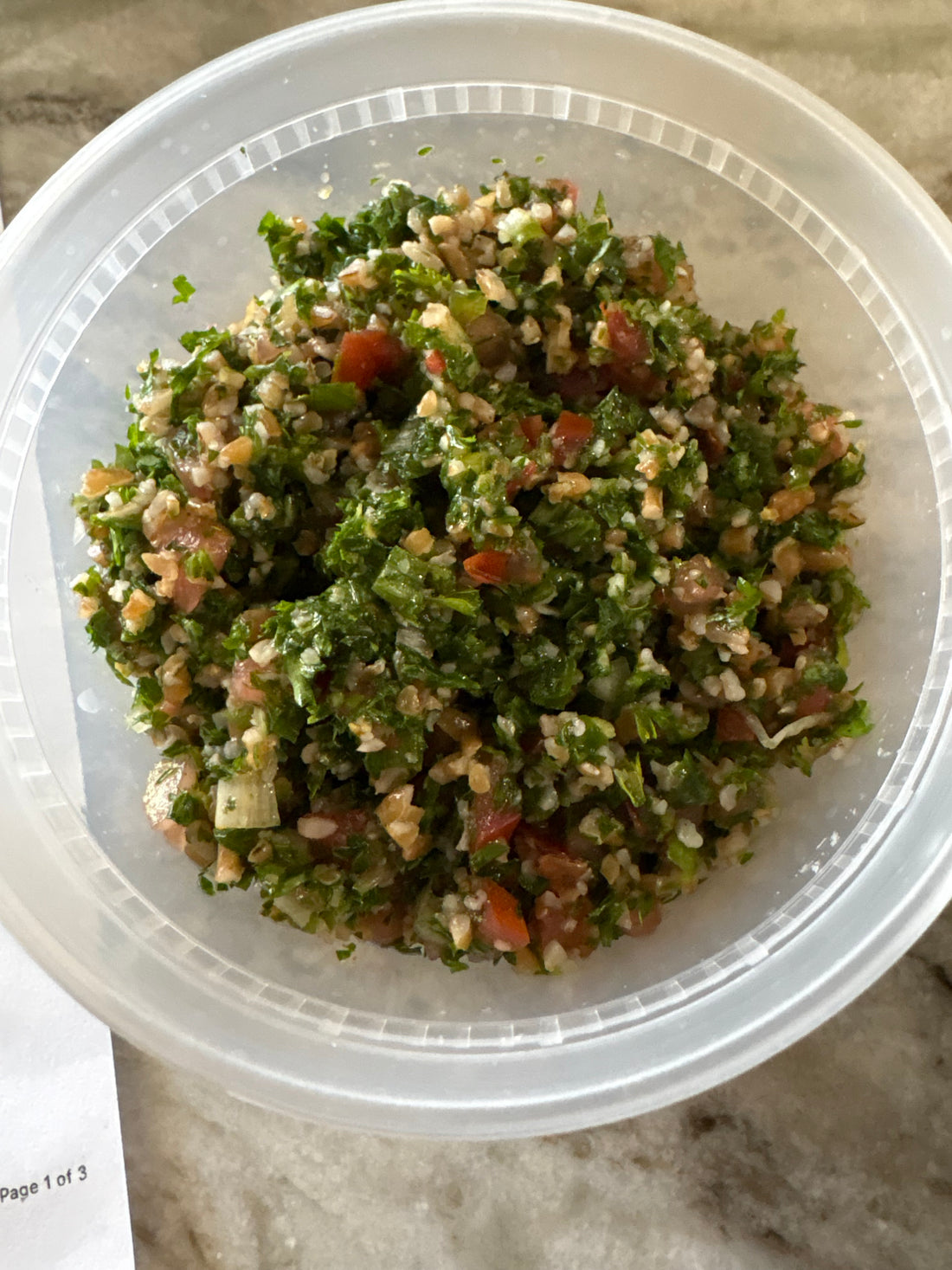 A bowl of tabouli salad with bulgur wheat, chopped parsley, tomato and cucumber