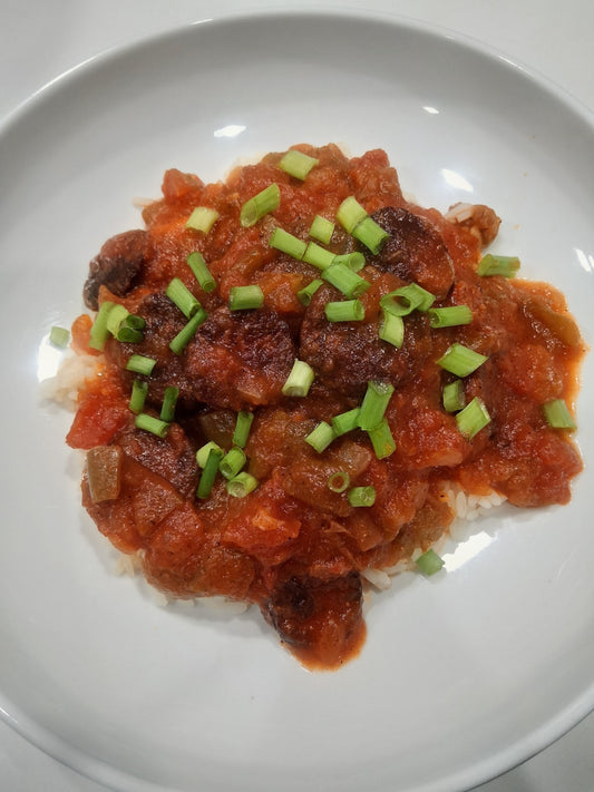 Smoked sausage creole in tomato sauce served over white rice with green onions